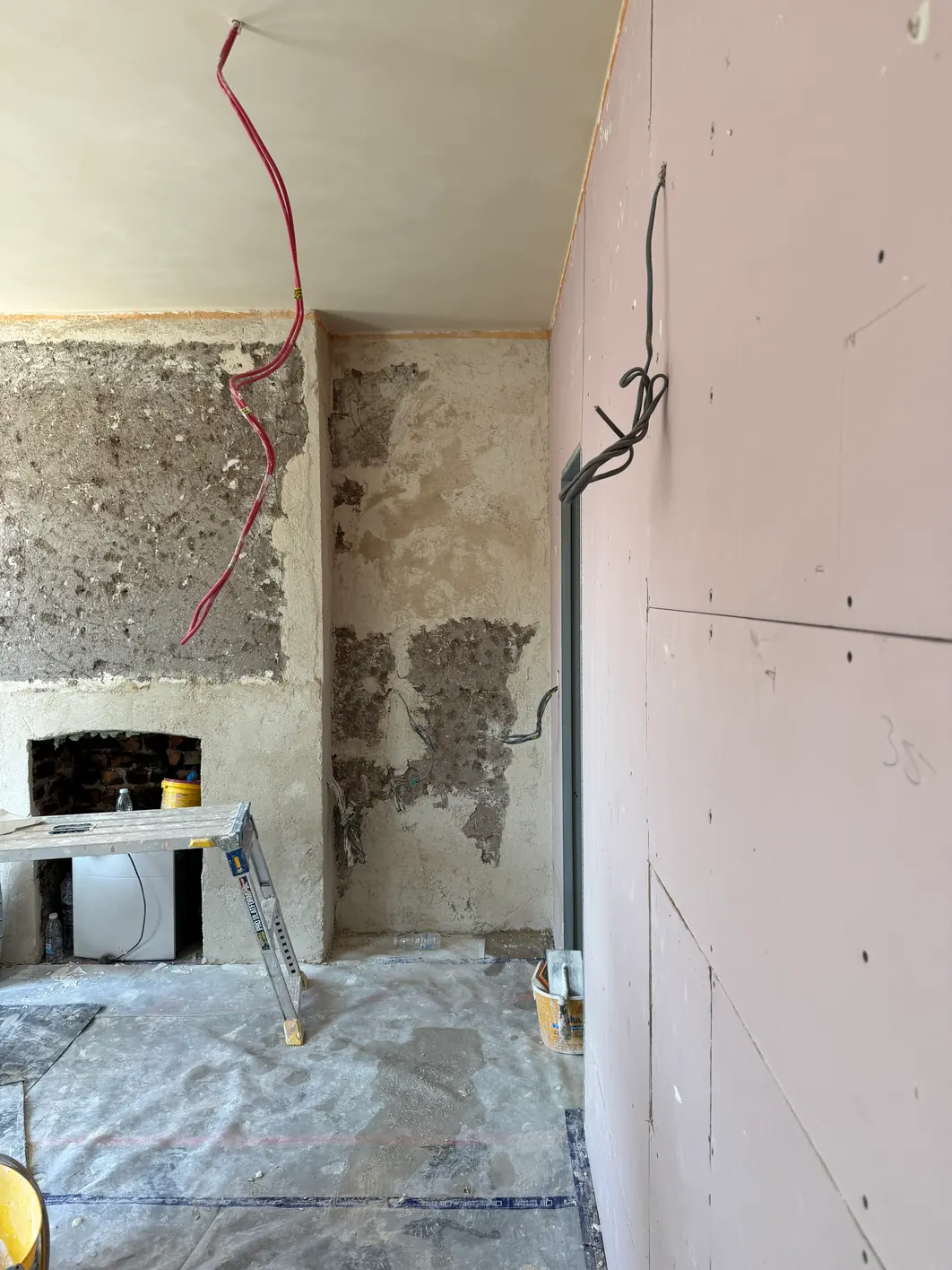 Chimney breast and narrow alcove carrying patch repairs in several different greys, with new pink plasterboard on the adjacent wall