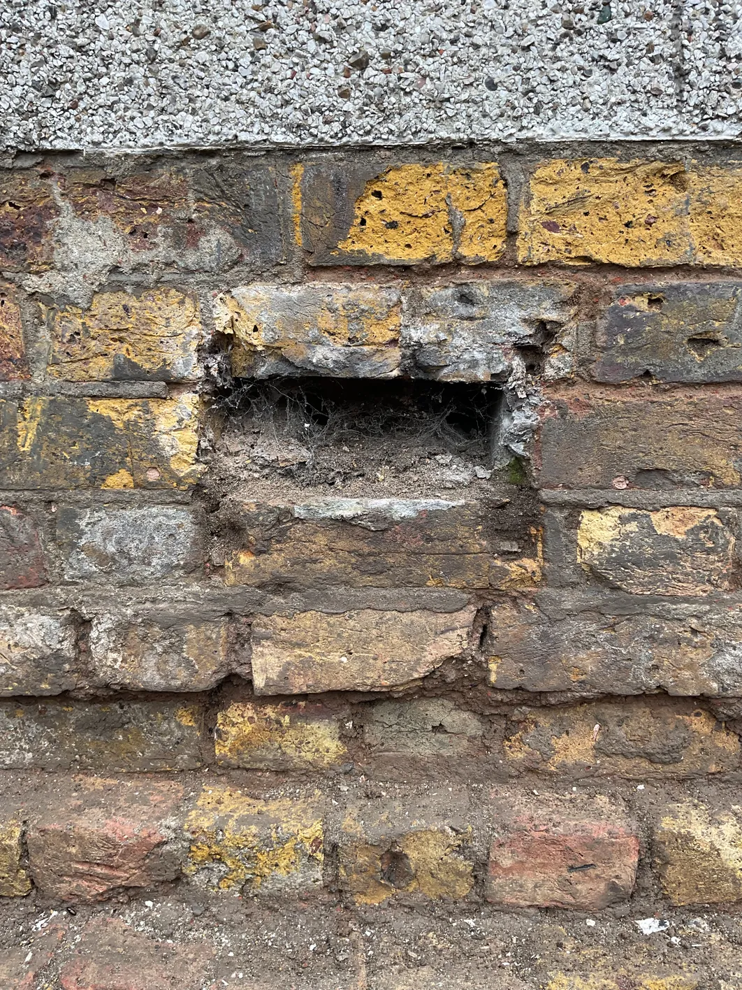 Horizontal cavity opening in brick wall, approximately 150mm wide, showing void behind failed cement mortar joint
