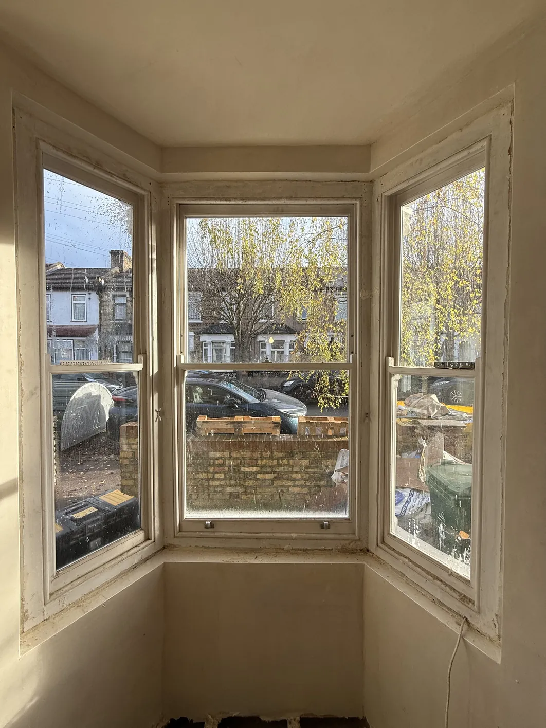 Interior view of a bay window with three panes showing newly plastered reveals and soffit in pale finish