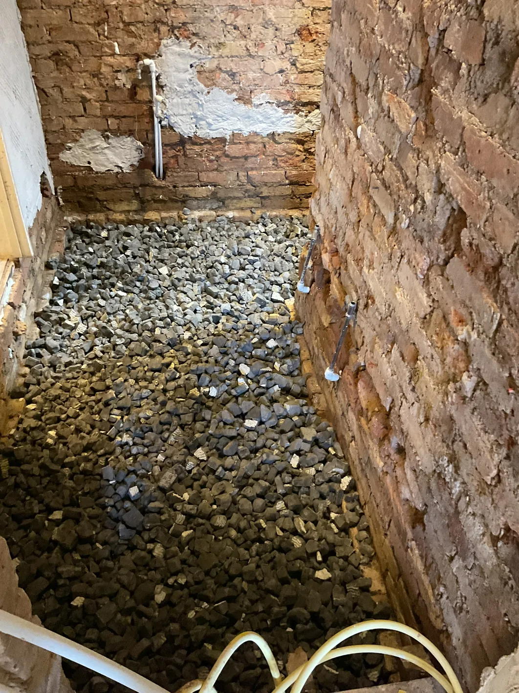 Recycled foamed glass gravel loose-laid across the sub-floor void, the insulating layer beneath a limecrete slab.